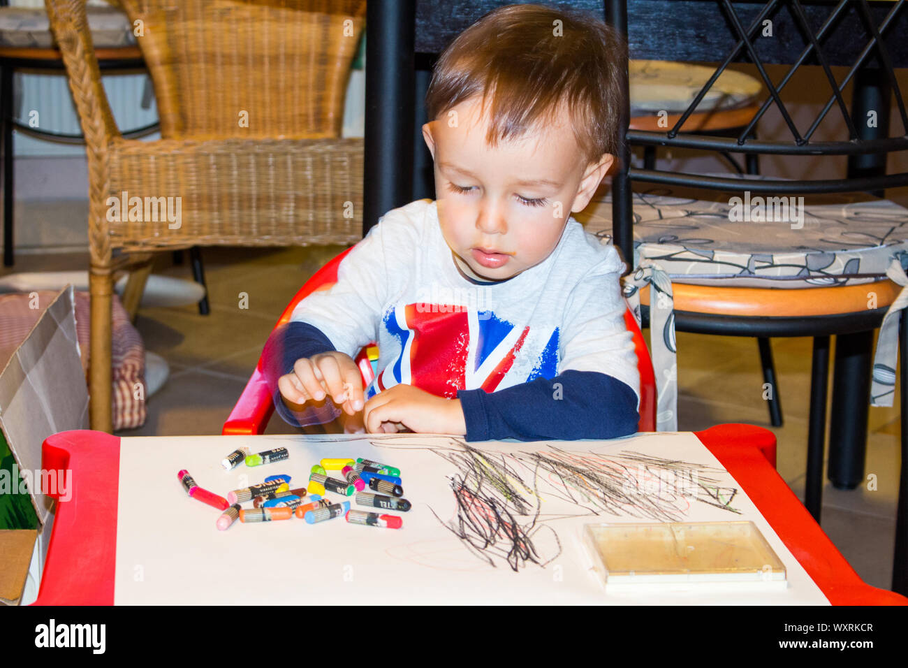 Der 3-jährige Junge, Kind, lernt zu Hause mit farbigen Buntstiften am Tisch zu zeichnen Stockfoto