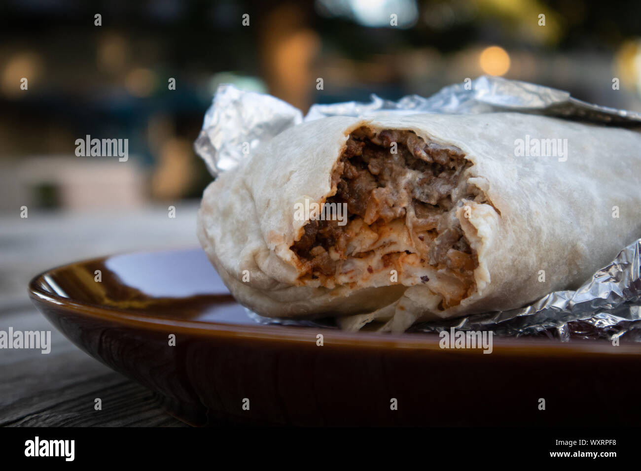 Carne Asada Burrito, die von einer Folie umhüllt wird offen auf den Tisch Stockfoto