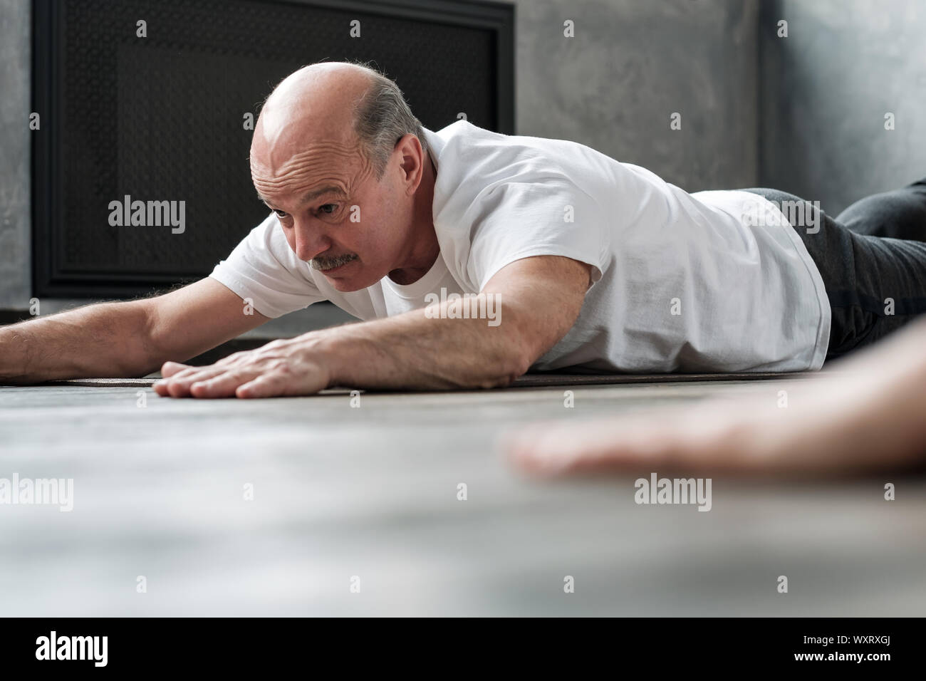 Senior Hispanic yoga Mann in Cobra oder Sphinx pose bhujangasana Variation in der Turnhalle. Superager gehen in für den Sport Stockfoto