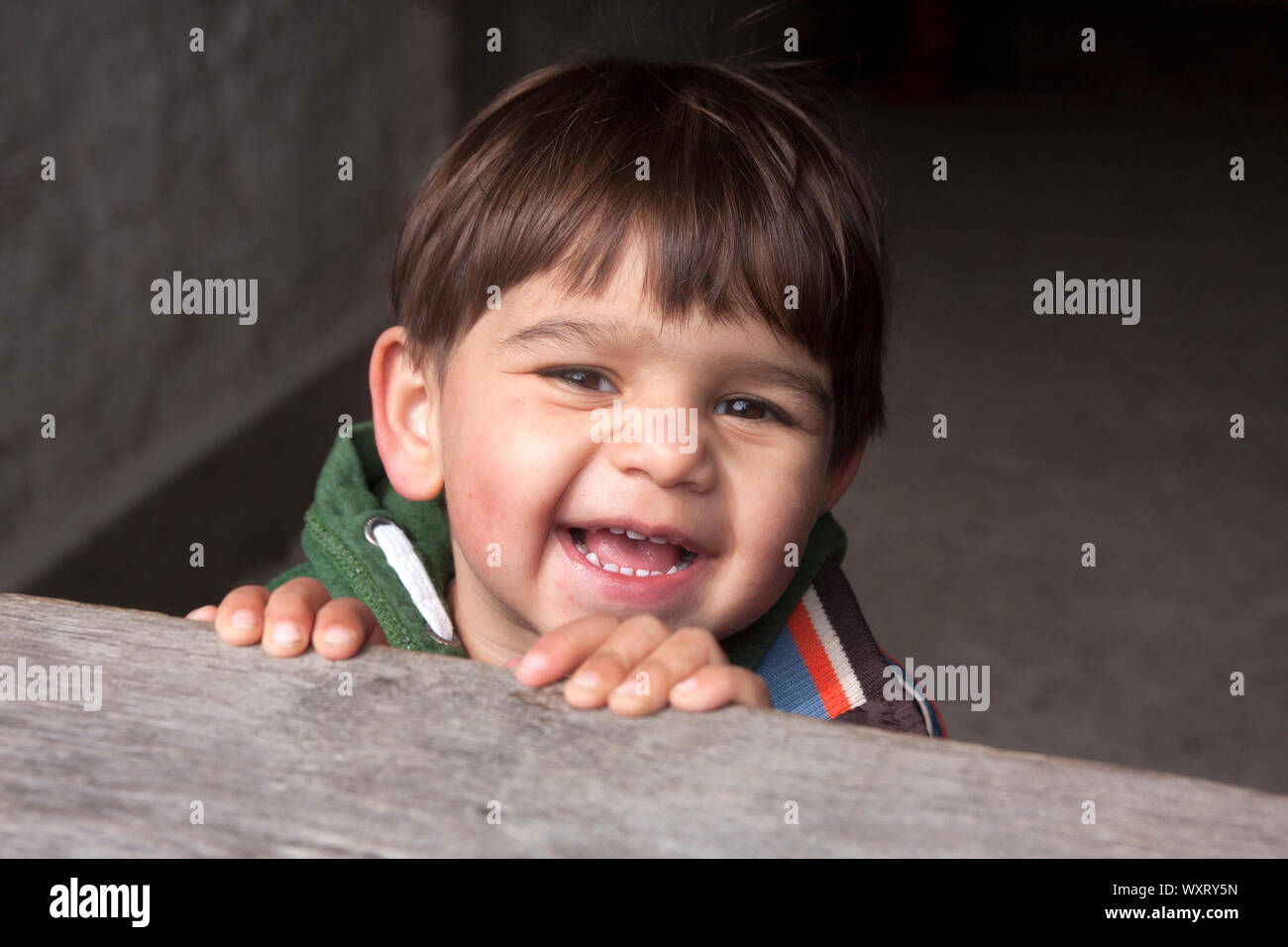 Happy little boy Peering über hölzernen Türrahmen Stockfoto