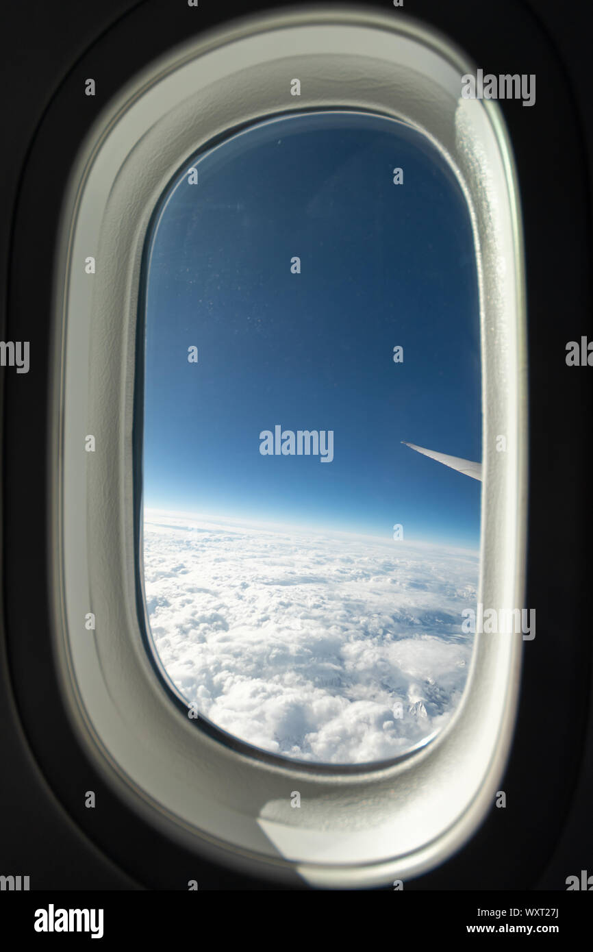 Volle Fensteransicht in einer Boeing 787 am Himmel an einem klaren Tag mit Bergen unten. Stockfoto