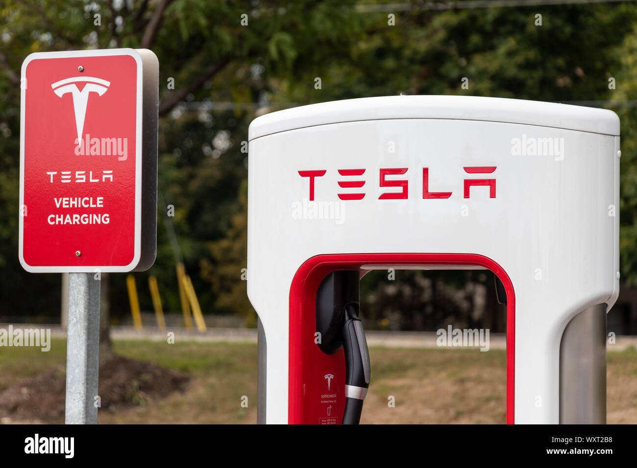 Oberseite des Tesla Supercharger und Ladekabel mit "Tesla Fahrzeug laden" Schild neben. Stockfoto