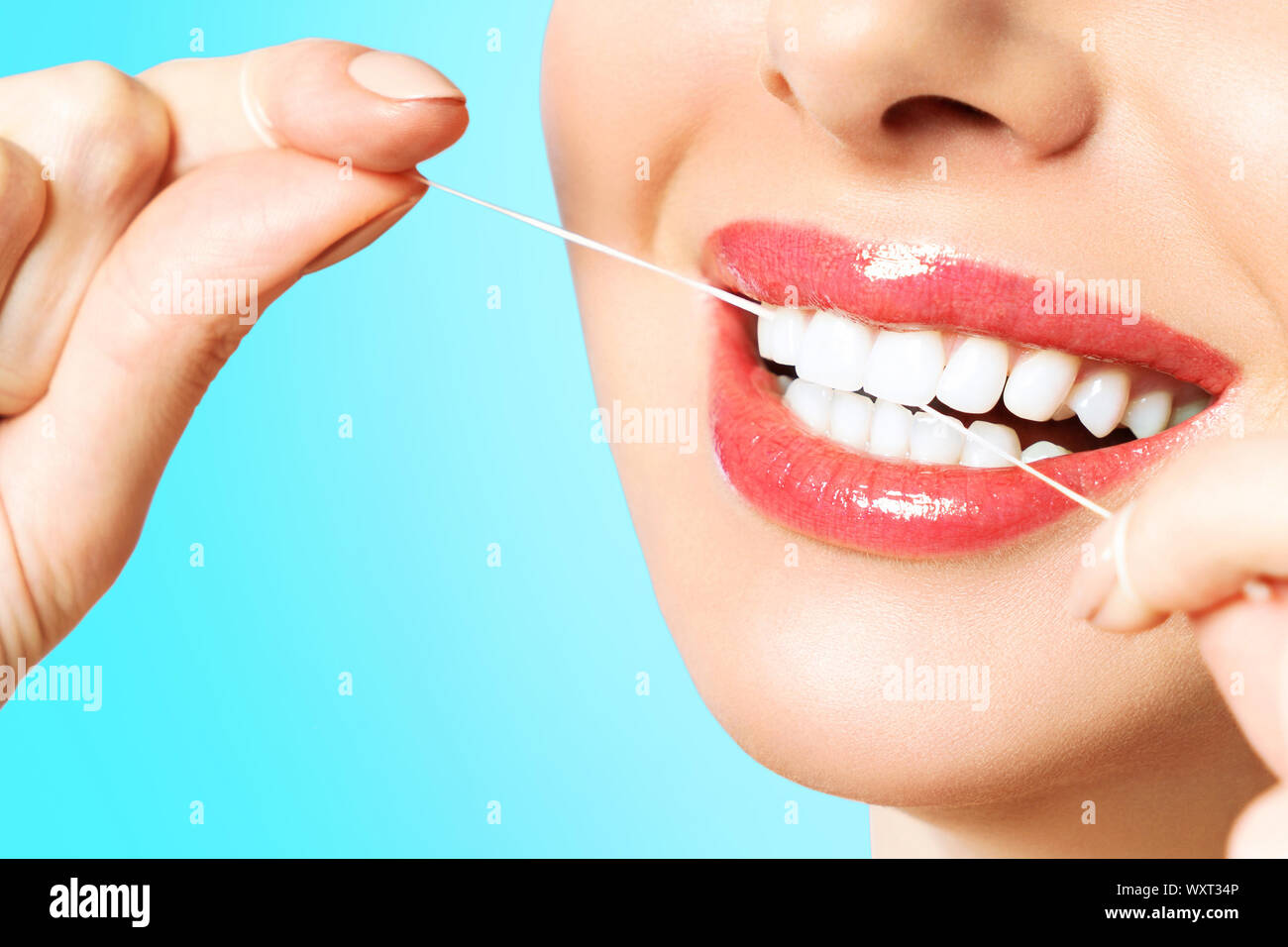 Junge schöne Frau ist bei der Reinigung der Zähne beschäftigt. Schönes Lächeln Gesunde weisse Zähne. Ein Mädchen hält einen Zahnseide. Das Konzept der Mundhygiene. Stockfoto