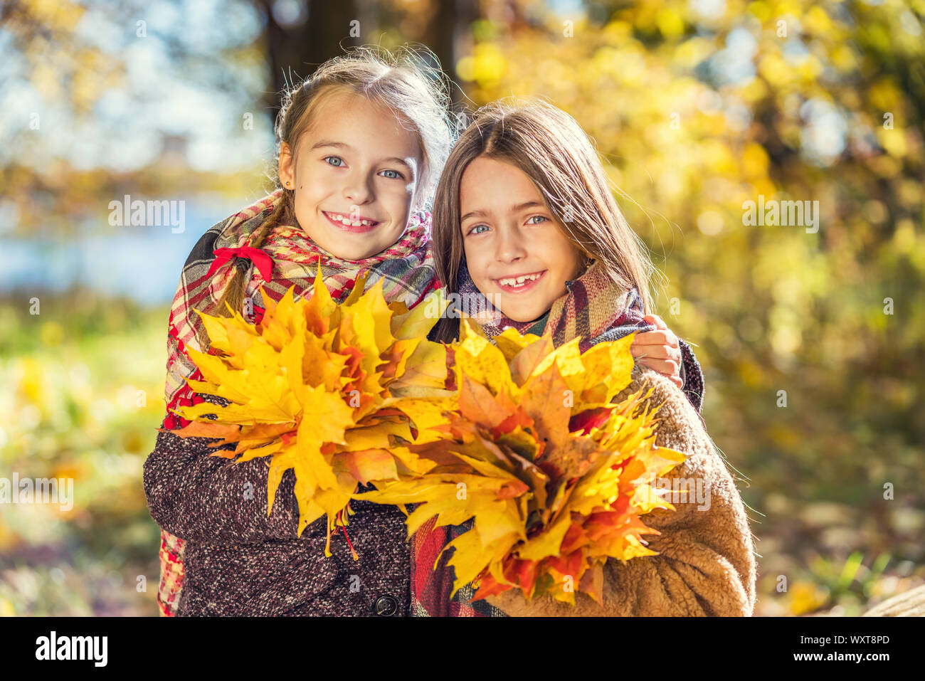 Zwei süße Lächeln 8 Jahre alten Mädchen zusammen Posieren in einem Park auf einem sonnigen Herbsttag. Stockfoto