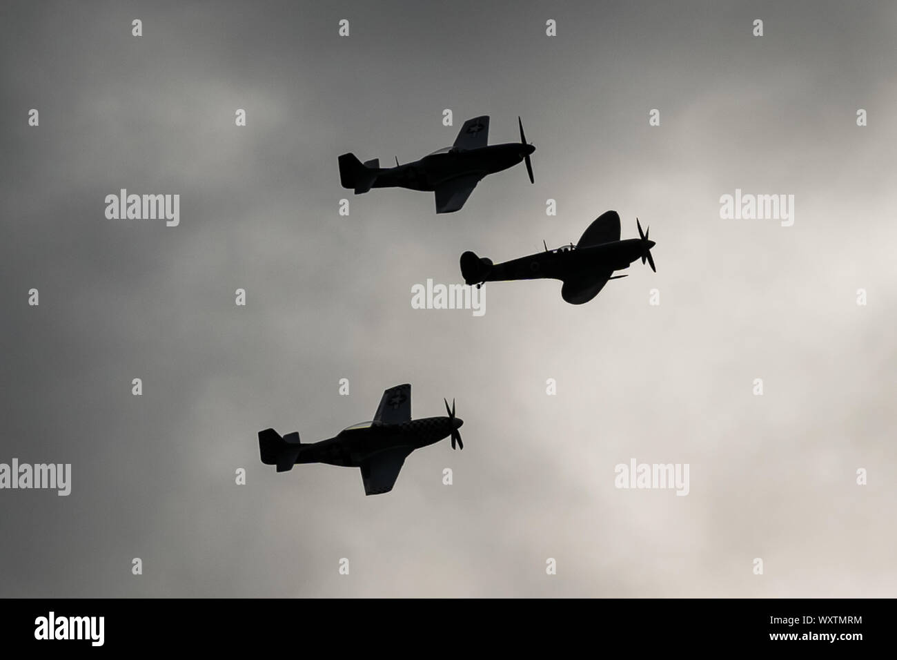 Die Vintage-themed Goodwood Revival. Großbritanniens größte jährliche Classic Car Show. Rolls Royce Merlin Spitfire Mk IX (Mitte) und zwei P51D Mustang Kampfflugzeuge in den Himmel drei Tage der Aktion ab, was einst RAF Westhampnet. UK. Stockfoto