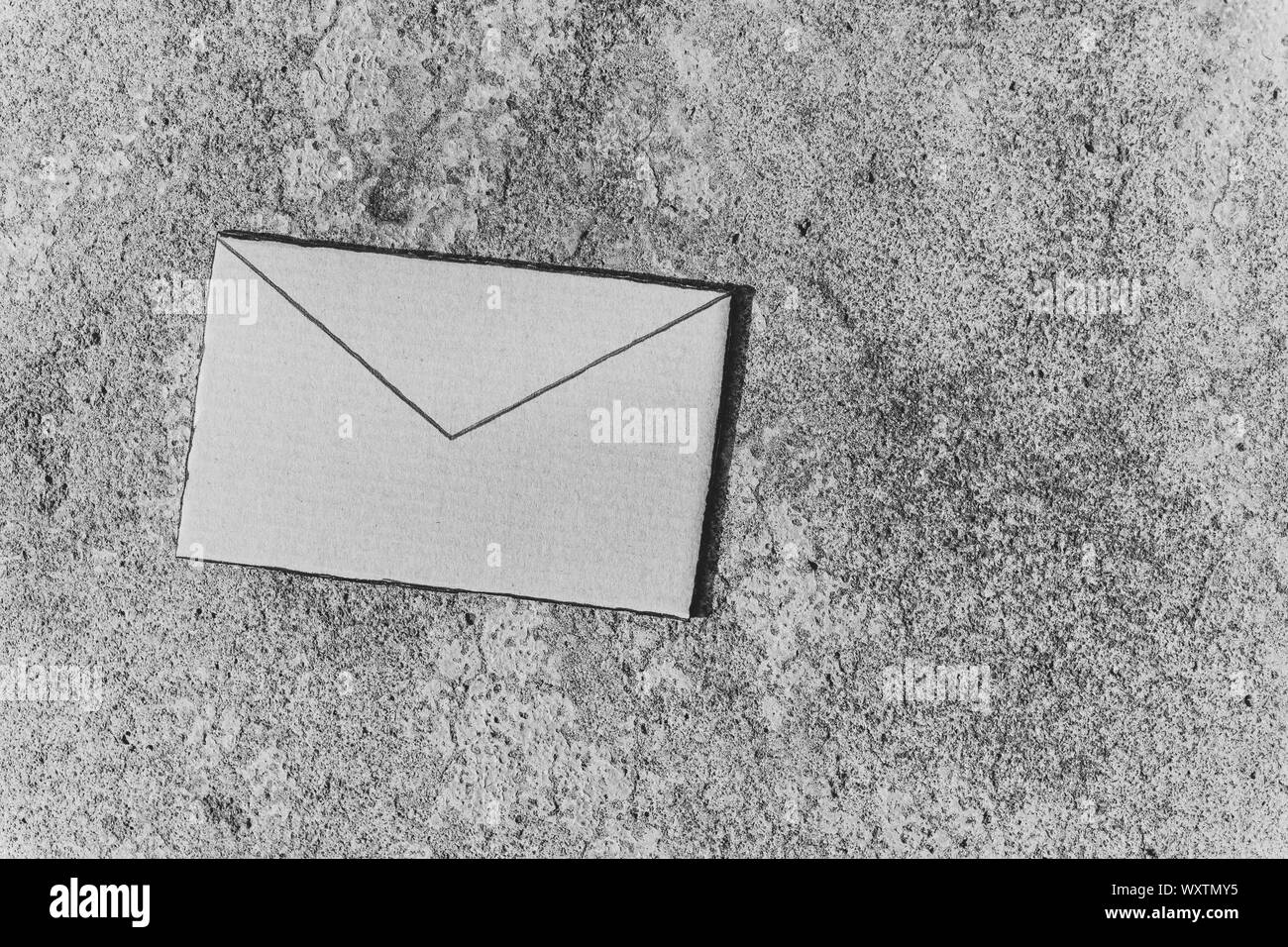 E-Umschlag Schild aus Pappe auf konkreten Hintergrund, minimalistisch, shot in Schwarz und Weiß mit Copyspace Stockfoto