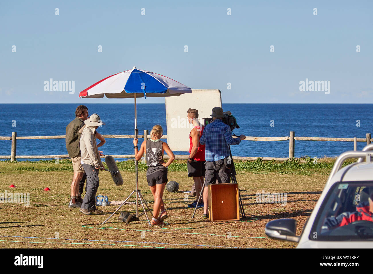 Schauspieler und Crew, darunter ein Sound Ausleger und Bediener der Kamera Filmen einen Outdoor Szene von Haus & entfernt Fernsehprogramm im Palm Beach, Australien Stockfoto