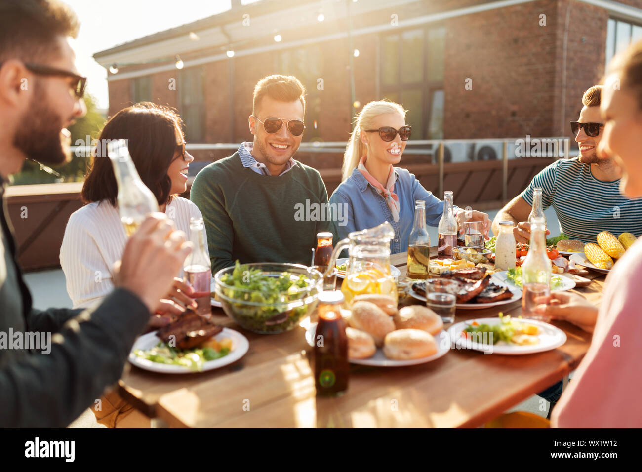 Freizeitaktivitäten und Personen Konzept - glückliche Freunde Essen und Trinken bei der Grillparty auf dem Dach Stockfoto