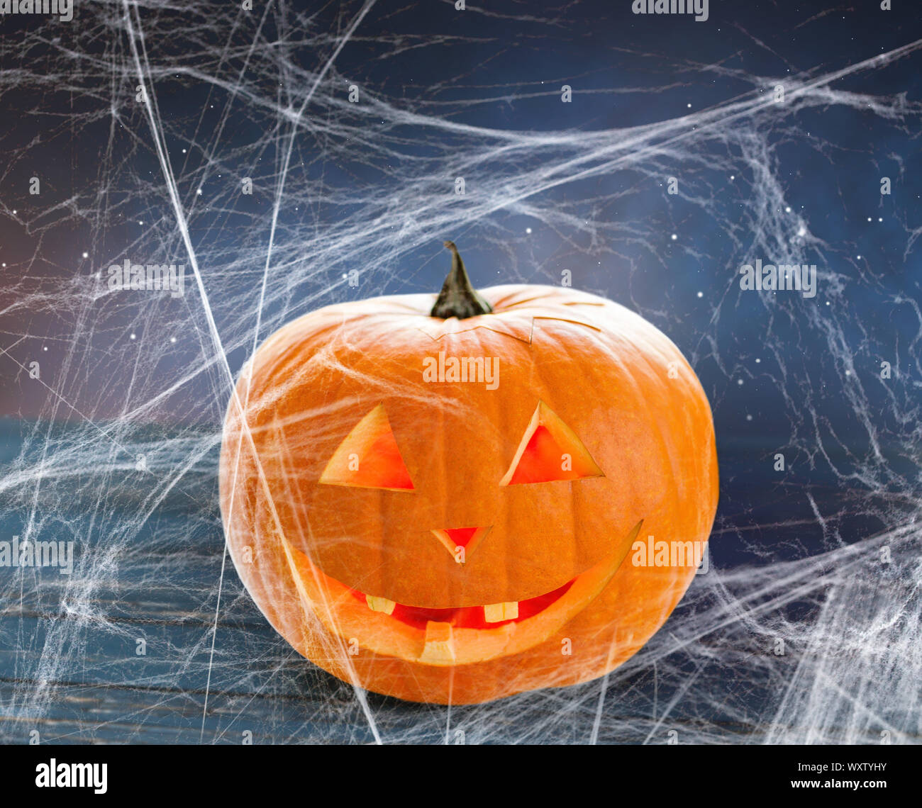Urlaub, Halloween und die Dekoration - Kürbis oder jack o lantern auf Tisch und Spiderweb über Sternenhimmel Hintergrund Stockfoto