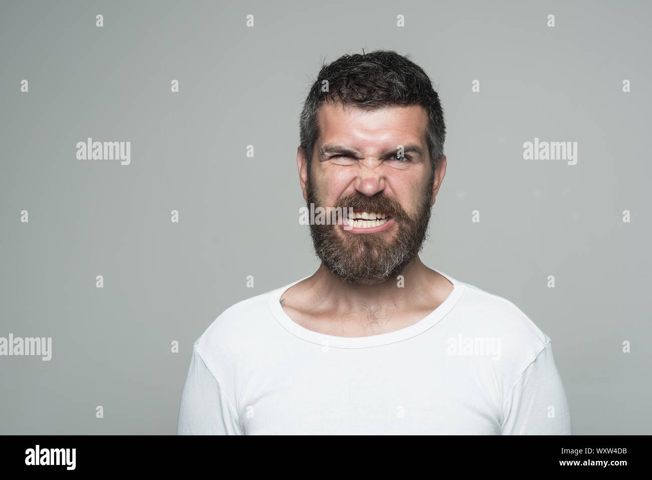 Hipster mit Verärgerten Gesicht. Gefühl und Emotionen. Kerl oder ein bärtiger Mann auf grauem Hintergrund. Friseur Mode und Schönheit. Mann mit langem Bart und Schnurrbart, cop Stockfoto