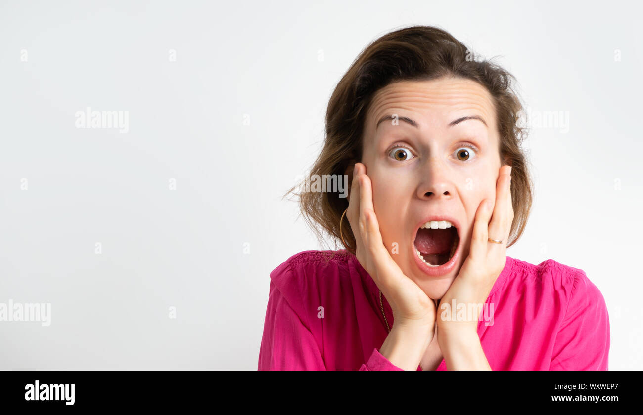 Bild einer aufgeregt schreienden jungen Frau, die in einem rosa Bluse isoliert über einen hellen Hintergrund. Stockfoto