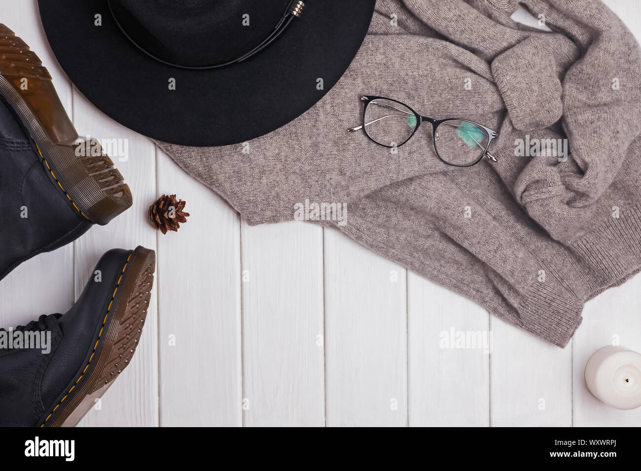 Feminine herbst Outfit auf dem weißen Holz- Hintergrund. Warmen gemütlichen Pullover, Hut und Stiefel Top View Stockfoto