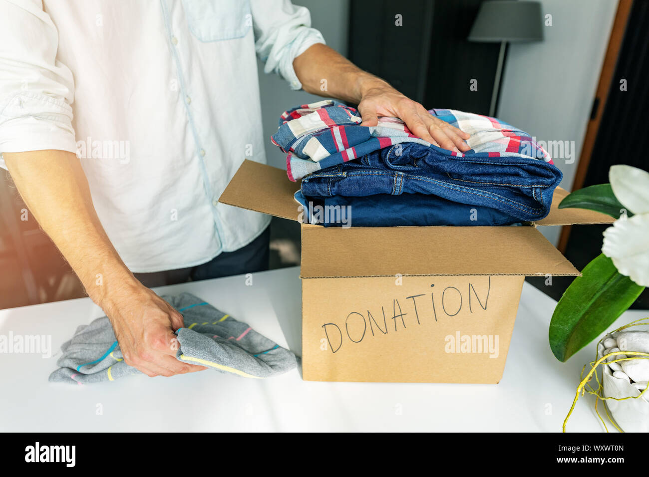 Nächstenliebe - Mann zu Hause bringen Kleidung in die cardboad Box für Spende Stockfoto