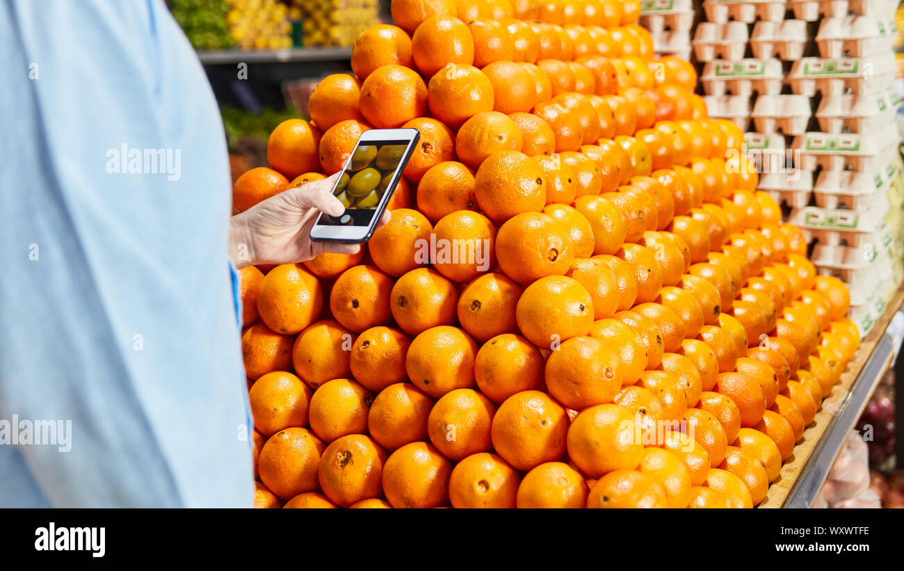 Kunde verwendet Smartphone App beim Kauf von frischem Obst im Supermarkt Stockfoto