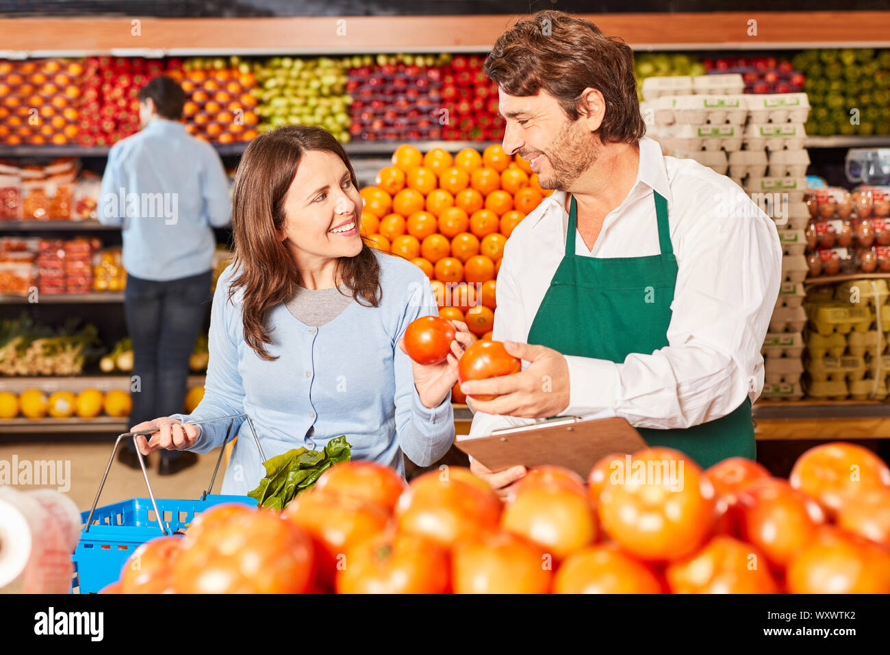 Junge Verkäufer im Supermarkt hilft Kunden Gemüse als Service zu kaufen Stockfoto