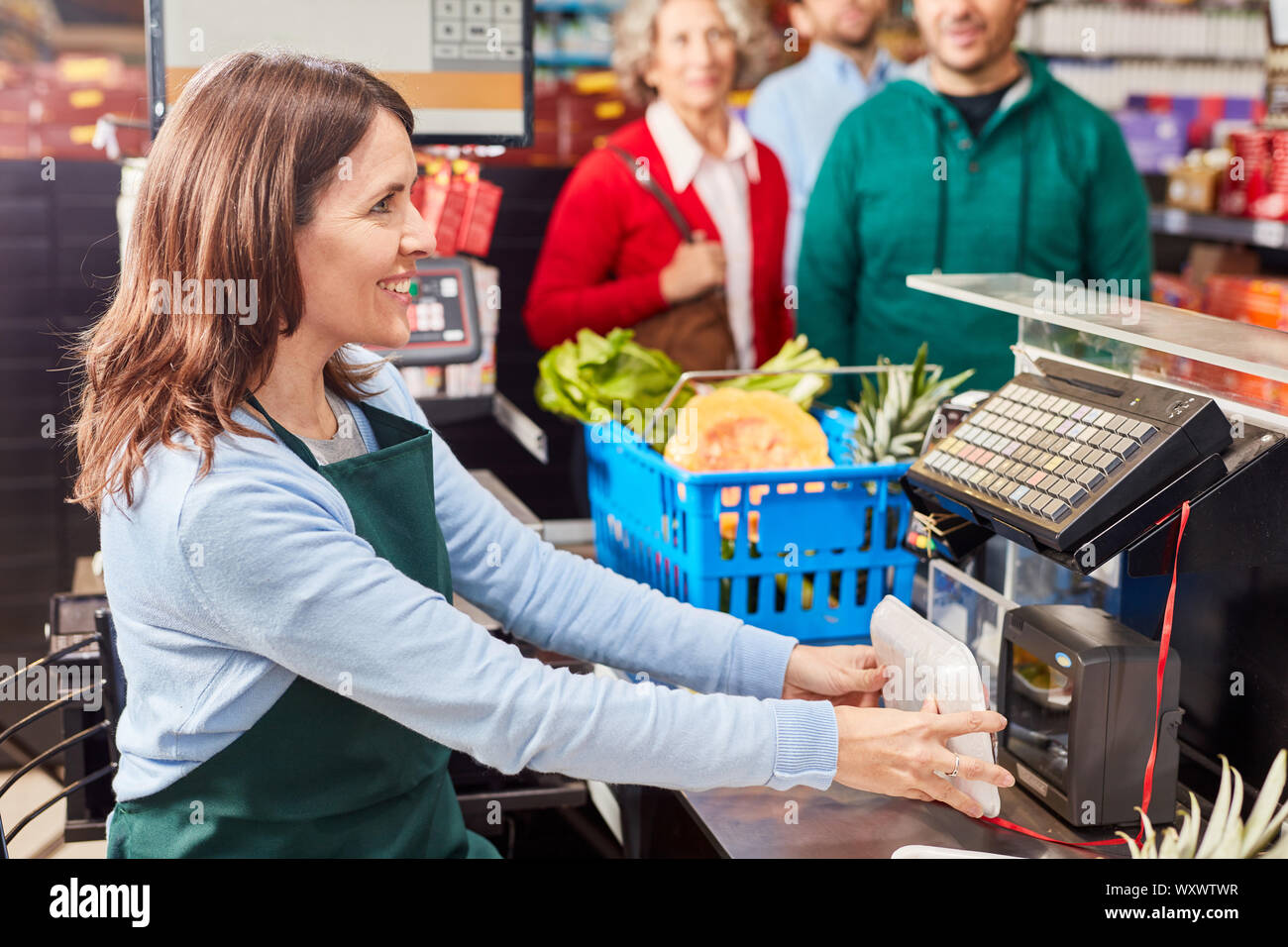 Lächelnde Kassiererin im Supermarkt Kasse nutzt Barcode Scanner Stockfoto