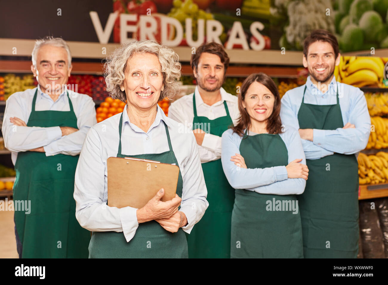 Glückliche Gruppe der Verkäufer im Supermarkt mit Market Manager und Auszubildende Stockfoto