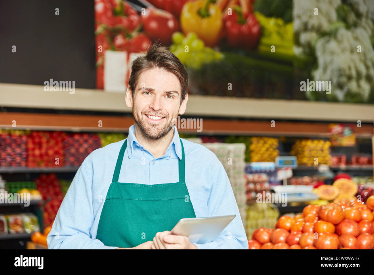 Lächelnde Menschen als Verkäufer oder Marktführer mit Schürze im Supermarkt Stockfoto