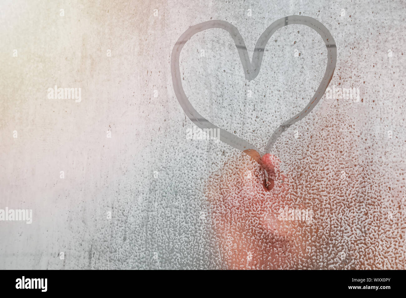 Erwachsene Person Finger zeichnen ein Herz Form auf der beschlagenen Glas mit Tropfen im Bad. Konzentrieren Sie sich auf das Herz Stockfoto