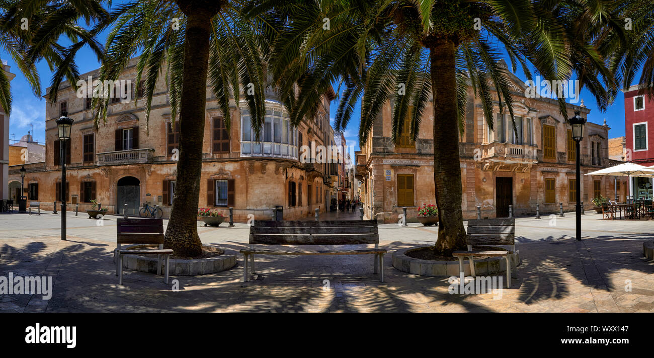 Panoramaaussicht auf der Bank unter Palmen in Ciutadella, Menorca mit traditionellen Straßen im Hintergrund Stockfoto