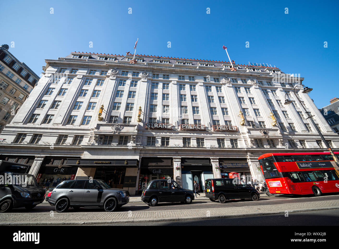 Strand Palace Hotel. Hotel im Art déco-Stil in The Strand, London, Großbritannien, mit schwarzen Taxis und einem roten Londoner Bus. Rote Telefonbox. Blauer Himmel Stockfoto