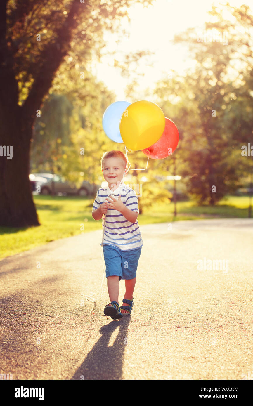 Cute adorable kleine Kaukasischen jungen Kleinkind Kind mit bunten Luftballons im Park Outdoor. Kid genießen zu spielen. Happy birthday Urlaub Feier. Stockfoto