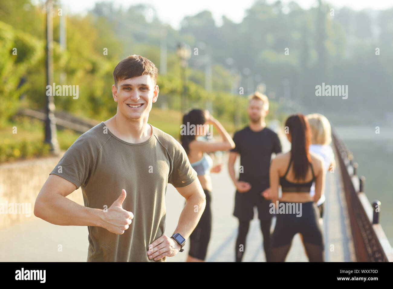 Sportlicher Kerl Lächeln auf dem Hintergrund der Freunde Athleten im Park Stockfoto