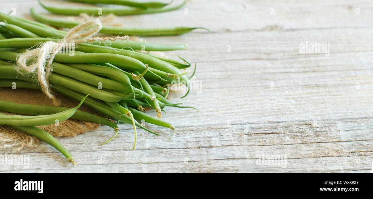 Frische grüne Bohnen auf einem hölzernen Hintergrund Stockfoto