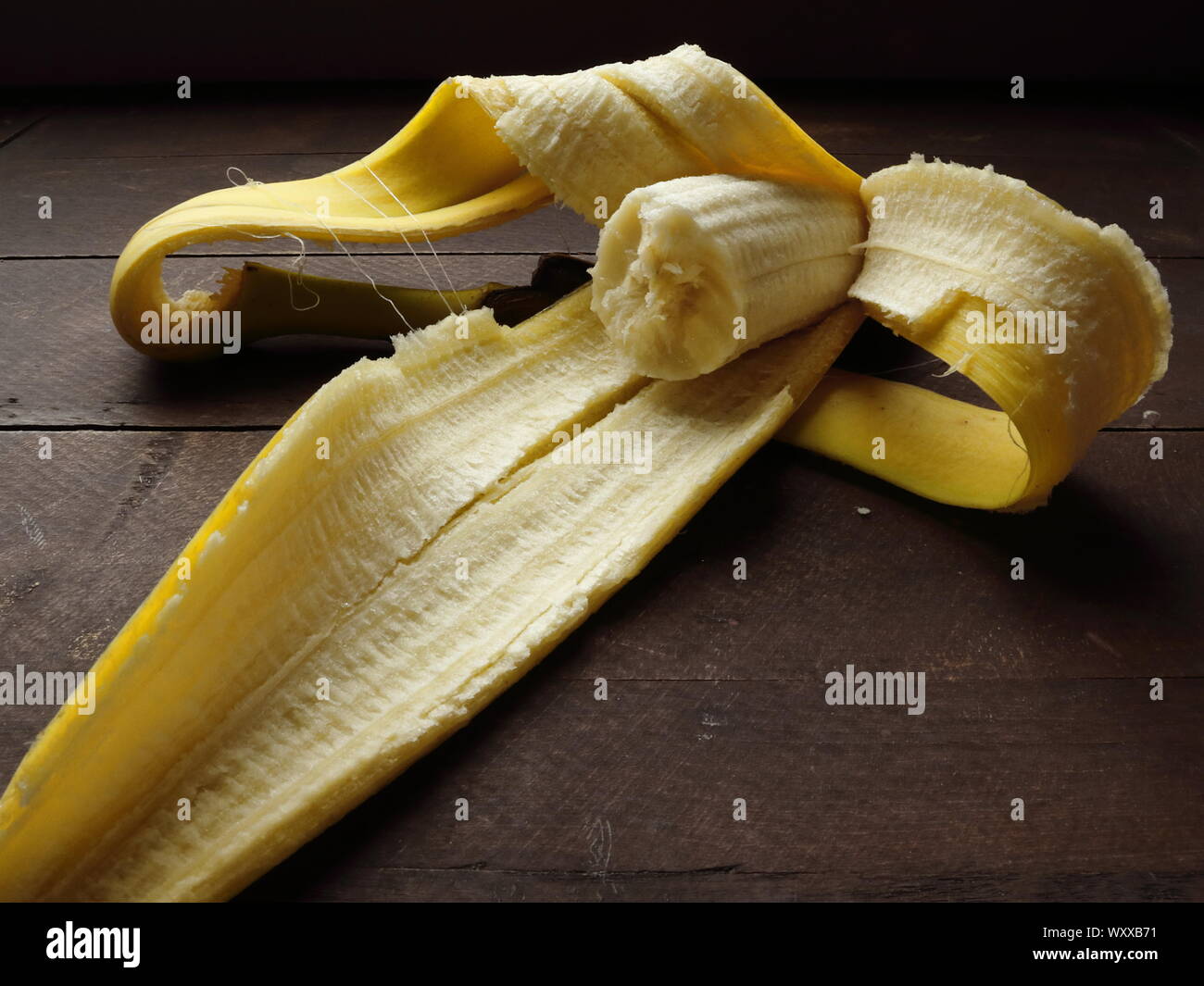 Teilweise Banane noch in der Schale auf rustikalen Holztisch gegessen Stockfoto