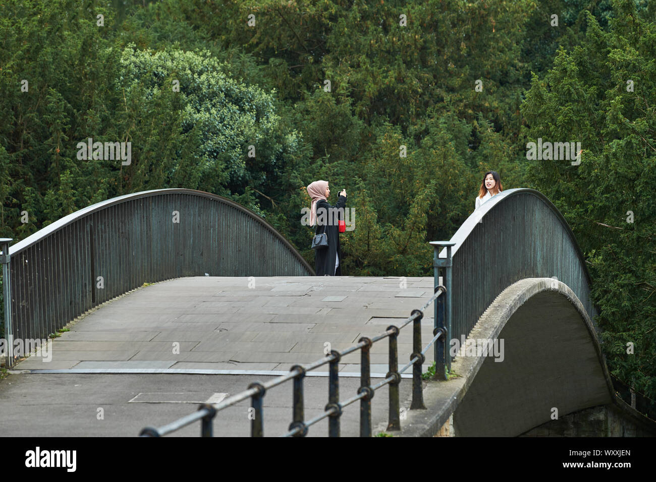 Zwei weibliche Touristen nehmen Sie ein Foto auf dem Buckel der Garret hostel Lane Brücke über den Fluss Cam, neben Trinity Hall College, Universität von Cambridg Stockfoto