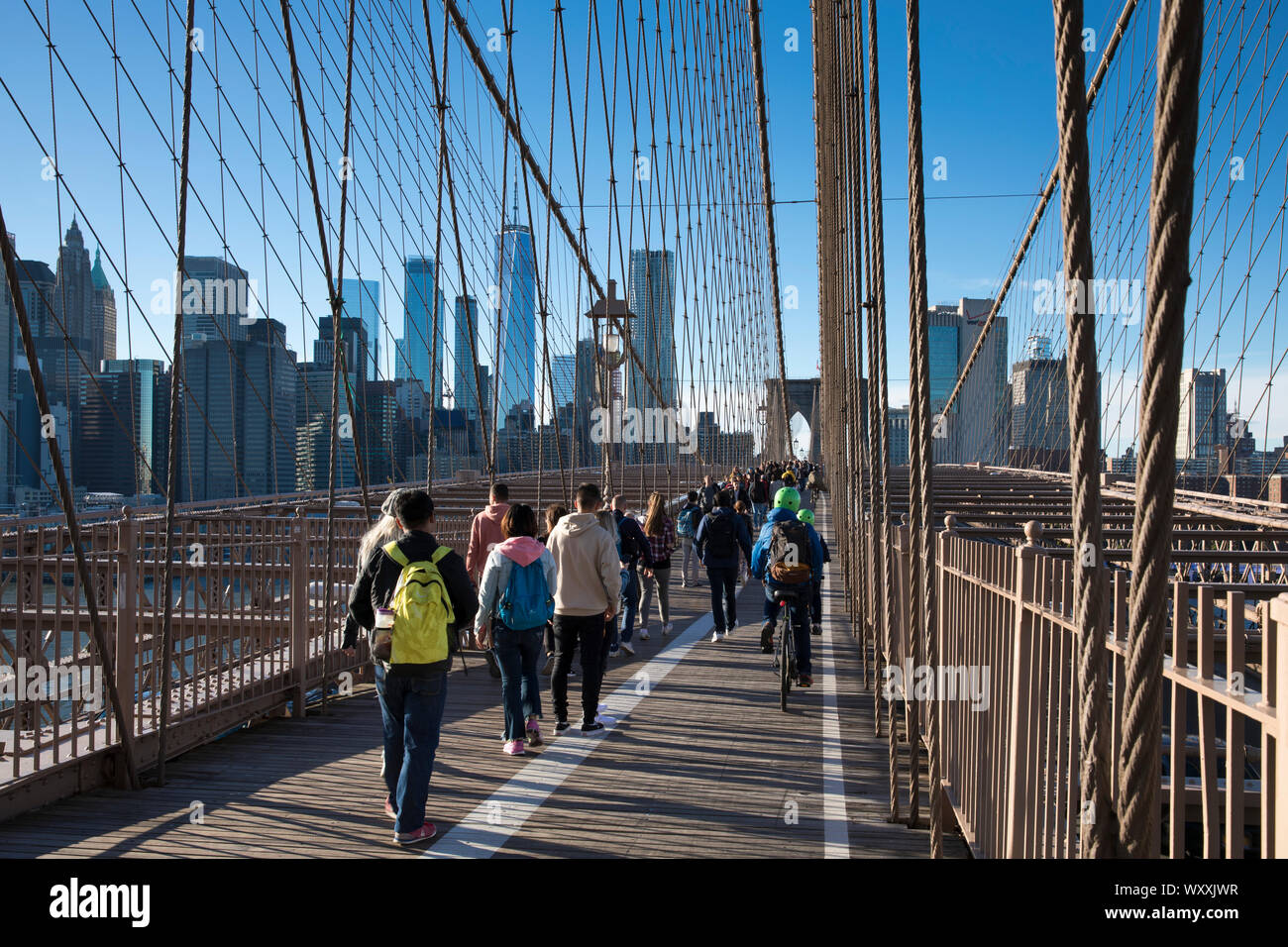 Touristen und Einheimische Spaziergang über die Brooklyn Bridge Richtung Manhattan, New York City Stockfoto