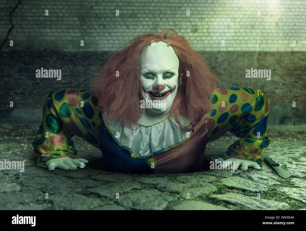 Grin Killer Clown steigt aus der Kanalisation Stockfoto