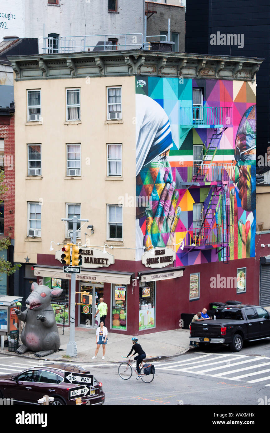 Straße Ecke Szene mit Radfahrer, Ampeln, Wandgemälde und Chelsea Square Markt Store an der West 18. Straße und Zehnten Avenue in New York City, USA Stockfoto