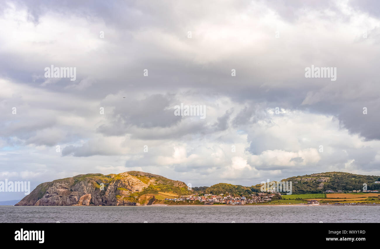 Ein Blick auf die llandudno Little Orme Landspitze Gefangen im Sonnenlicht unter einem wolkenlosen Himmel. Das Meer ist im Vordergrund. Stockfoto