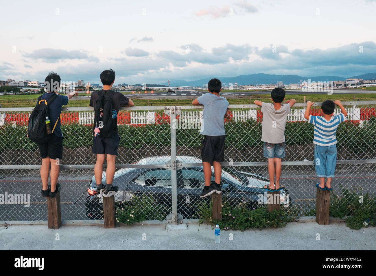 Fünf Jungen watch ein Flugzeug Start in die Umzäunung des Taipei Songshan Airport, Taiwan Stockfoto