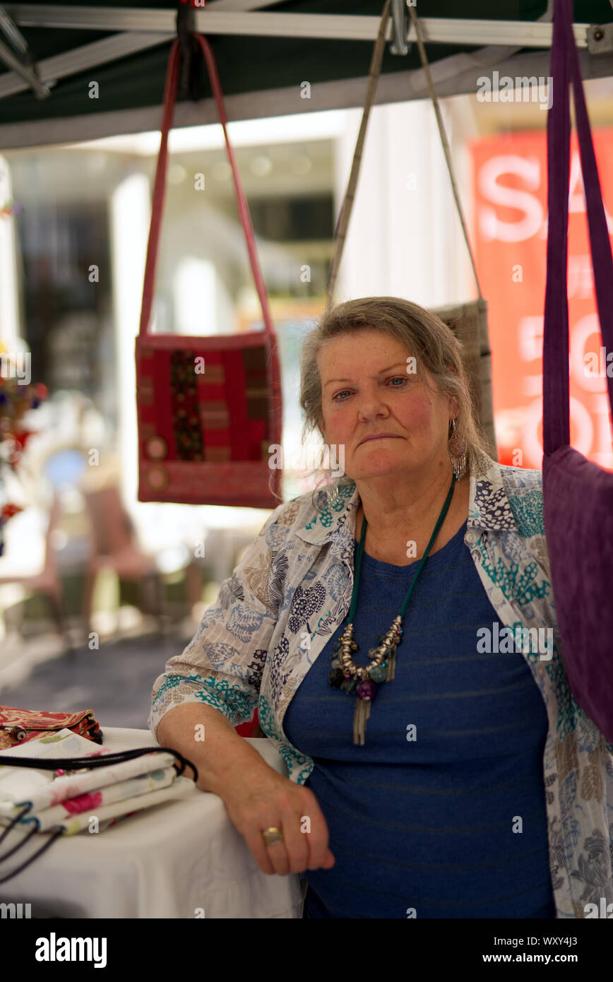 Portrait von Frau ihren Verkauf von künstlerisch gestalteten Handtaschen zu Brunnen, Marktplatz, Brunnen Somerset Stockfoto