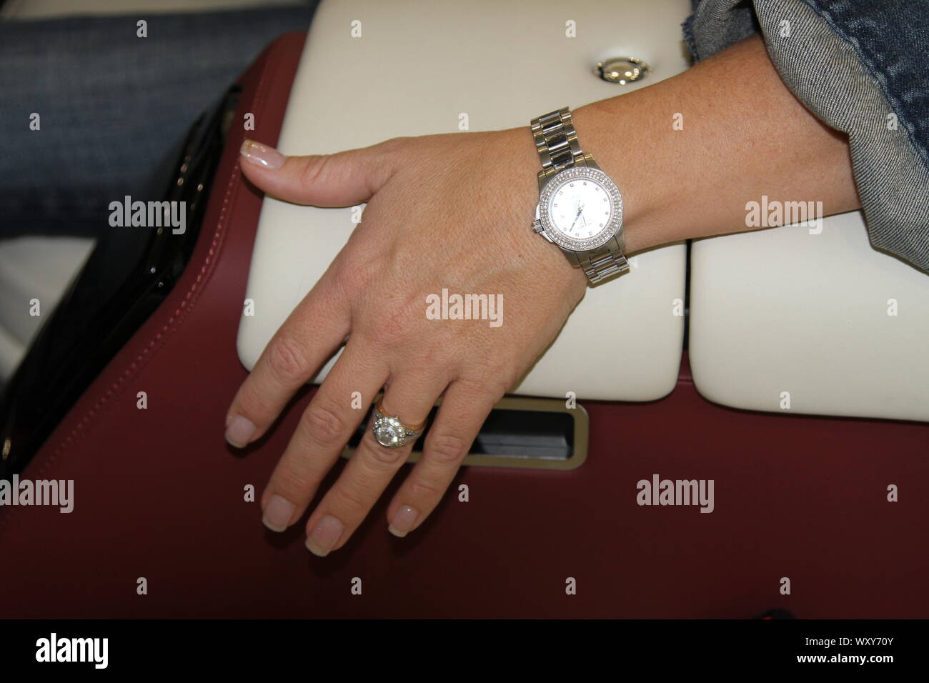 MUMTREPRENEUR. Frau sitzt in einer teuren Luxus AUTO MIT IHRER LINKEN HAND verziert mit einem VERLOBUNGSRING UND HOCHZEIT RING RUHT AUF DER MITTELKONSOLE. Eine teure Uhr wird getragen auf ihrem linken Handgelenk. Luxusgütern. Schmuck. Armbanduhr. Feminin. Fraulich. Gesund. Gesunde Haut. IN DER BLÜTE DES LEBENS. Ehe. SYMBOL DER EHE. Trauring. Luxuriöses, modernes Leben. Das moderne Leben. Moderne KRAFTFAHRZEUGE. PRIVATE AUTOS. PRIVATE FAHRZEUGE. Leder Innenausstattung von High-end-Fahrzeug. Authentische Bildsprache. Unternehmer. Mumtrepreneur. Mädchen Chef. Unternehmerinnen. Stockfoto