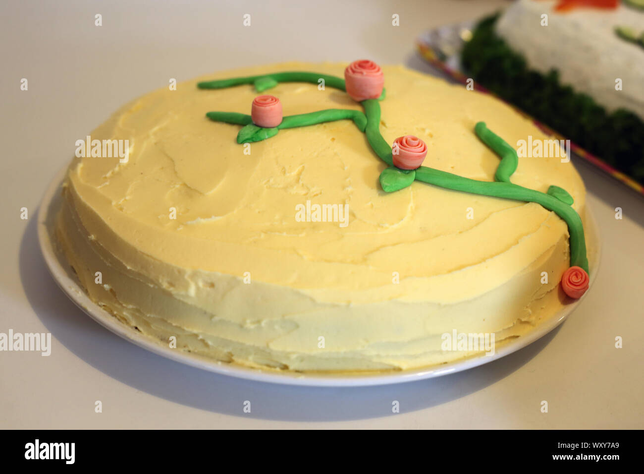 Orange und Schokolade gewürzte Kuchen mit gelben buttercream Frosting und kleine Rosen als Dekoration. Hausgemachte Konfektion ideal für Familienfeiern. Stockfoto