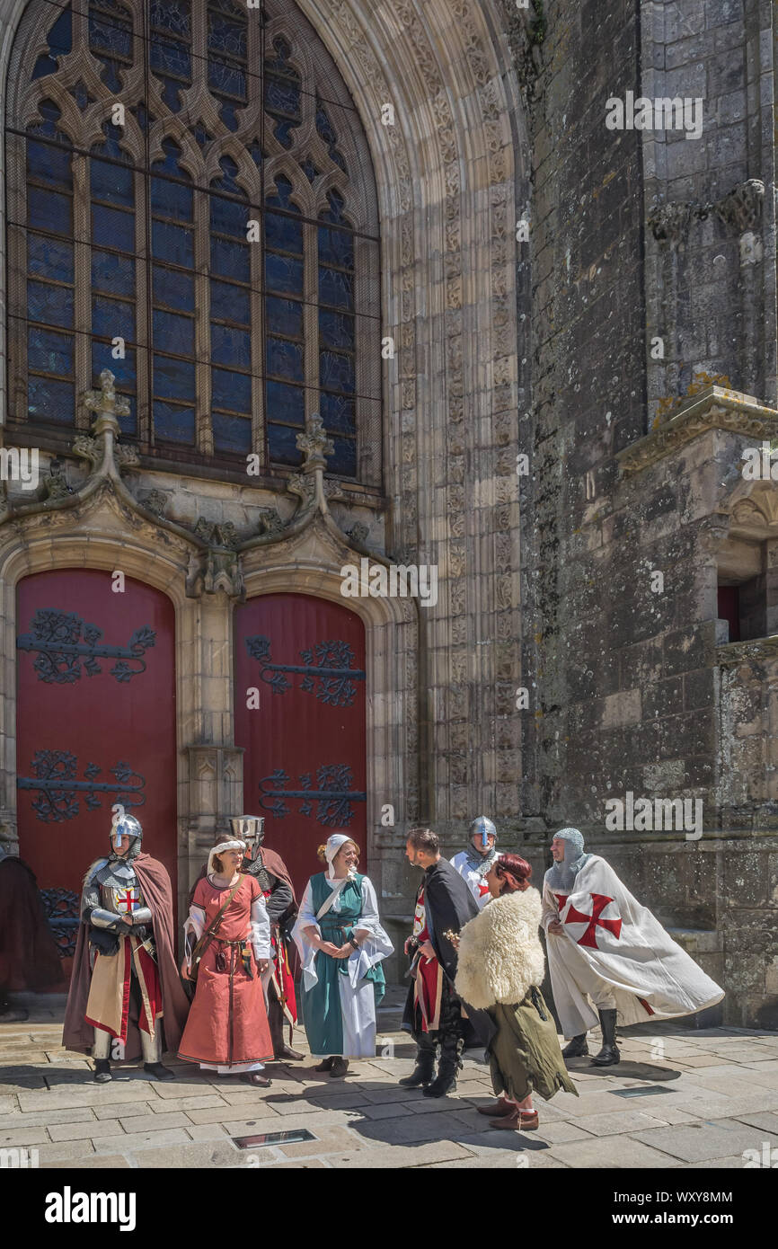 Eine Gruppe von drei Frauen, die im täglichen Mittelalterliches Kleid und fünf Männer in Crusader Kostüme außerhalb Große Rote Kirche Türen an der mittelalterlichen Festival in Guerand Stockfoto