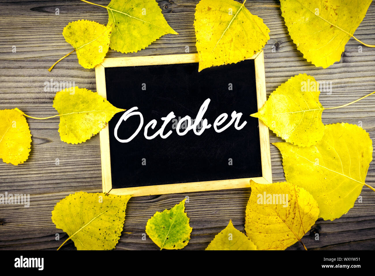 Bunte gelben Blätter im Herbst auf hölzernen Tisch und Tafel geschrieben Oktober Text, Herbst Jahreszeit Konzept Stockfoto