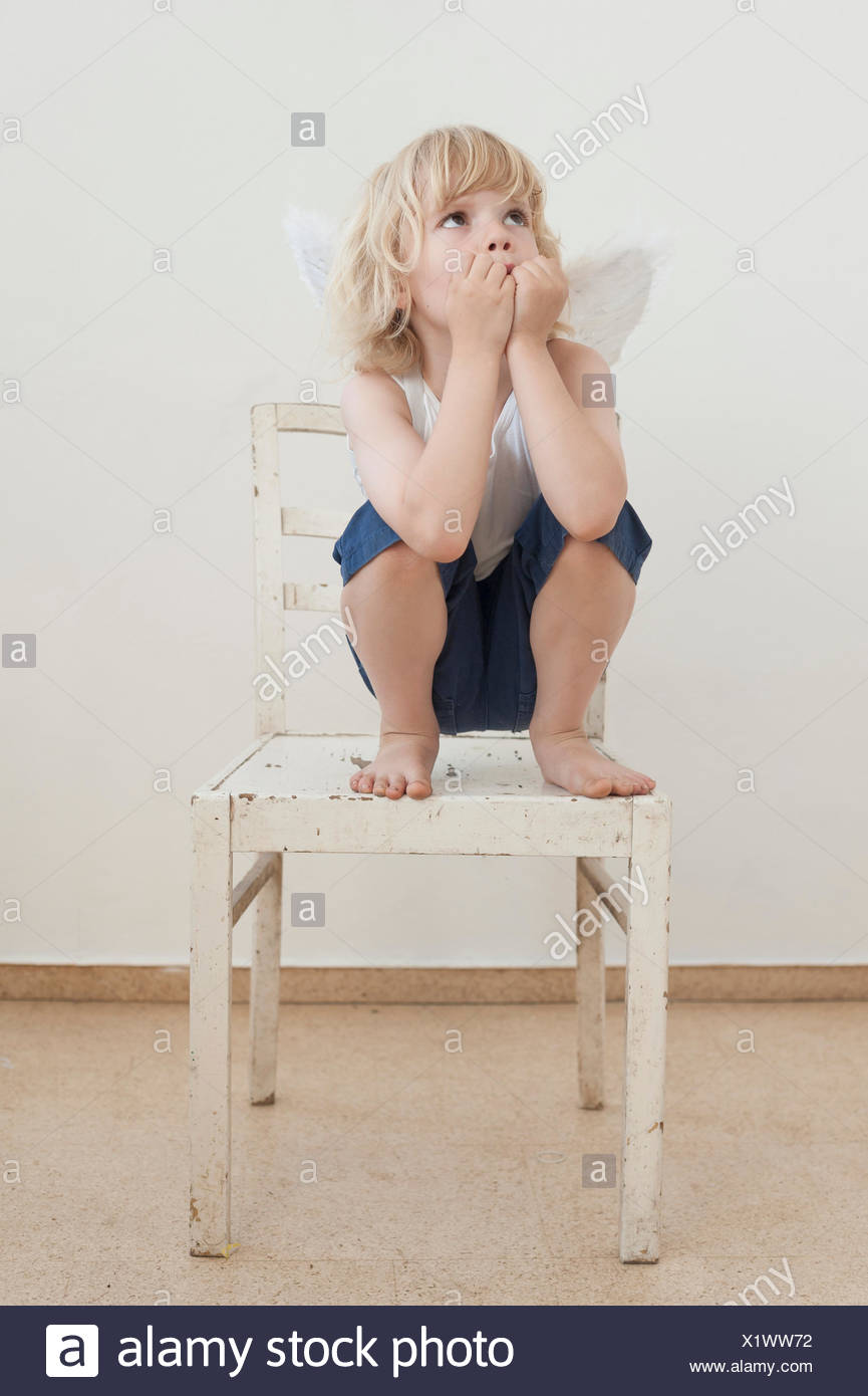 Porträt eines kleinen Jungen mit Winkel Flügel hocken auf einem Stuhl  Stockfotografie - Alamy