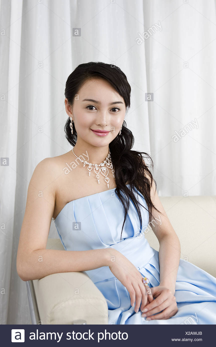 Lachelnde Junge Frau Tragt Ein Blaues Kleid Gekleidet Auf Sofa Stockfotografie Alamy