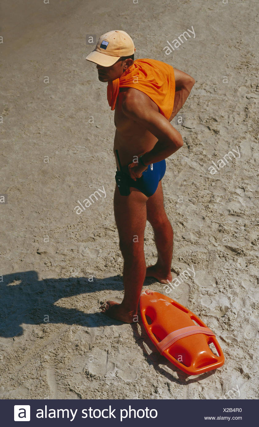 Rettungsschwimmer Ständer Strand Seitenansicht Leute Mann Besetzung Sonnigen Sandigen Strand Strand Kontrolle Beobachtung Kontrolle Rettungsmann überwachung Sicherheit Rettungsring Baywatch Boje Baywatch Ganzkörper Badehose