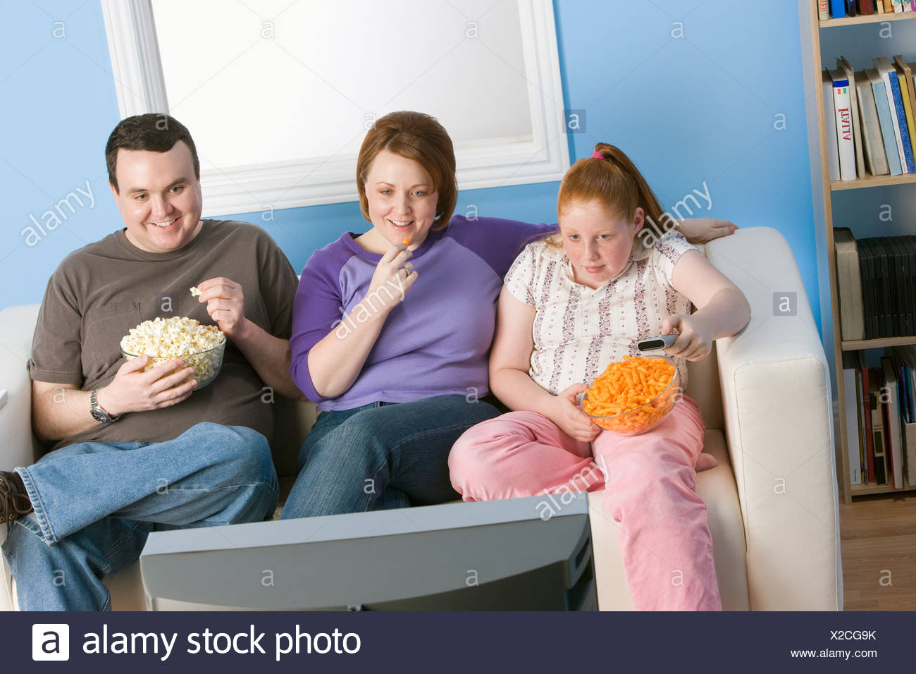 Familie Vor Dem Fernseher Auf Sofa Mit Ubergewicht Stockfotografie Alamy