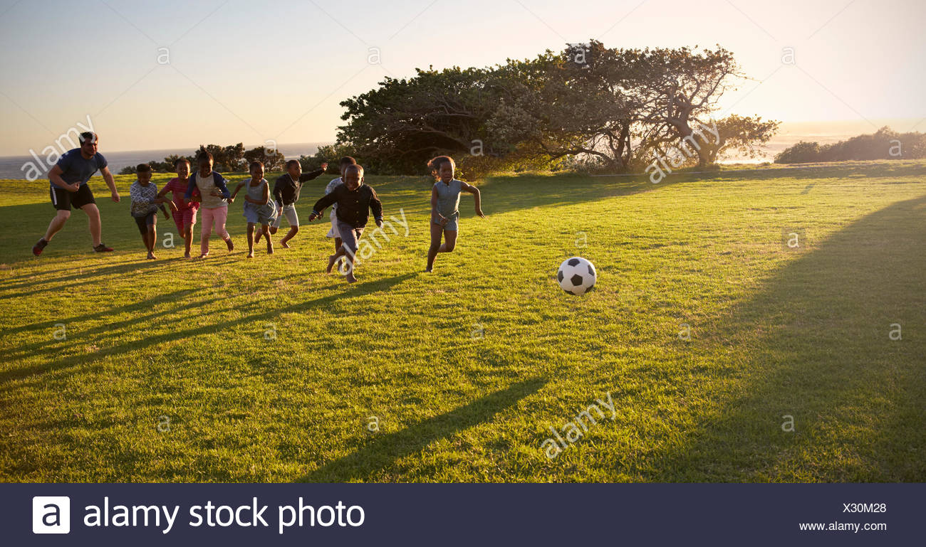 Lehrer und Grundschule Kinder spielen Fußball in einem Feld ...