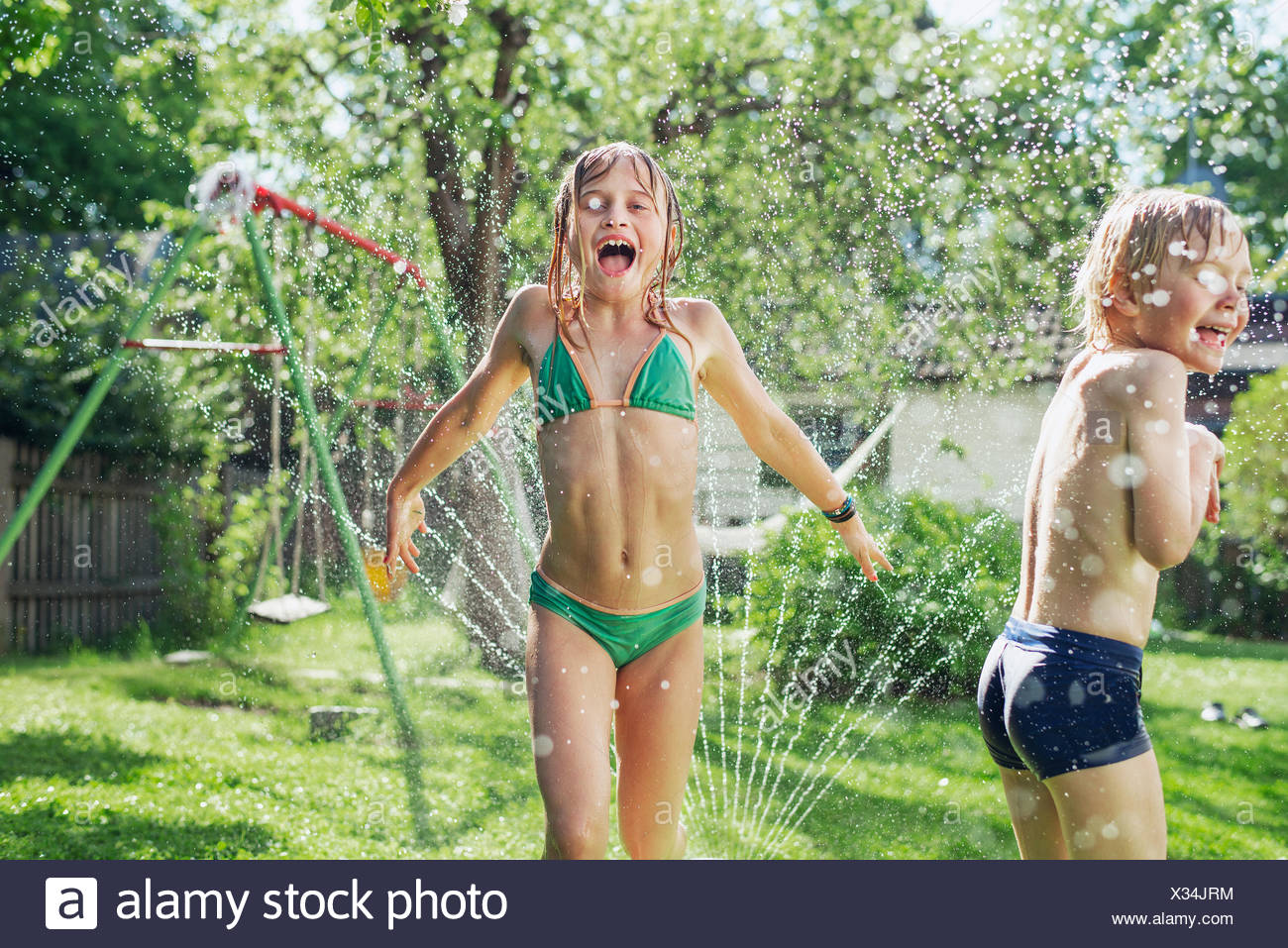 Mädchen und Jungen spielen mit Wasser im Garten Stockfoto ...