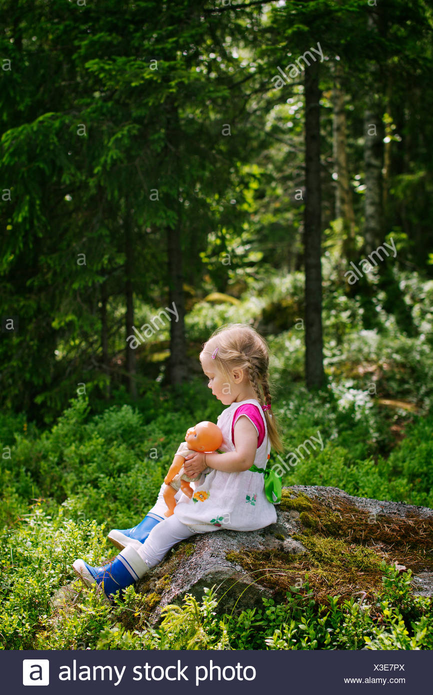 Finnland, Paijat-Hame, Seitenansicht der Mädchen (2-3) mit Puppe auf Felsen sitzend Stockfoto