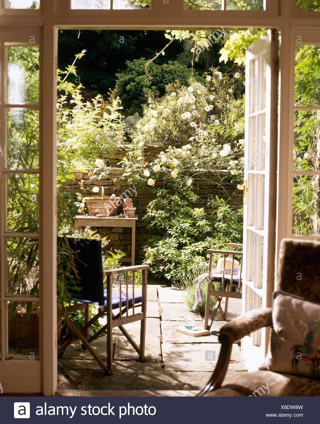 Ferienhaus Wohnzimmer Mit Schiebeturen Zum Garten Mit Stuhle Auf Der Terrasse Und Rosa Rosen An Der Wand Offnen Stockfotografie Alamy