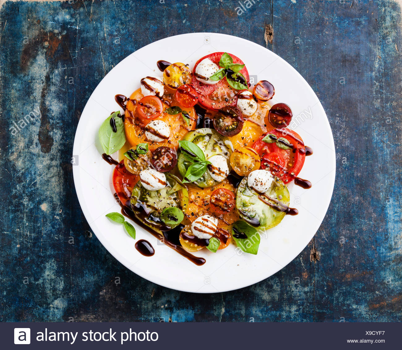 Bunte Tomaten-Salat mit Mozzarella und Balsamico-Essig auf blauem ...