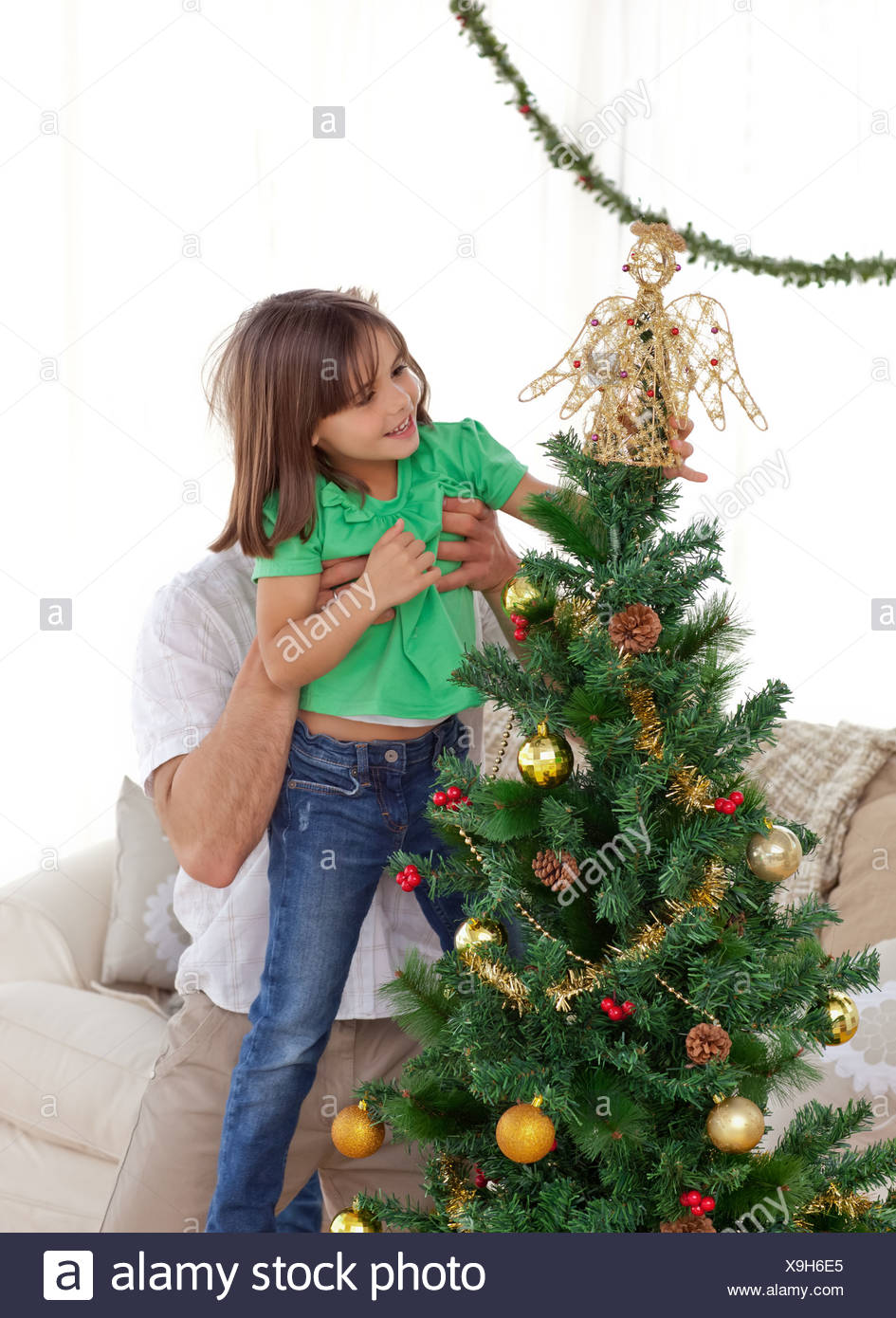Aufmerksamen Vater hält ihre Tochter um den Weihnachtsbaum schmücken Stockfoto